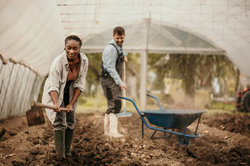 Shot of a young female farmer working with her husbant in their greenhouse.