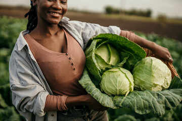 Cheerful black woman holding a fresh raw crop from her farm field. Organic farm and sustainable...