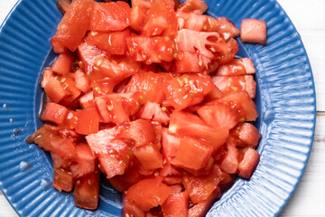 Sliced tomato on a blue plate. Fresh tomato without peel.