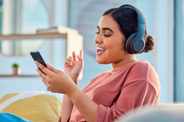 Woman on couch, smartphone and headphones for music, audio and connectivity in lounge. Hispanic female, girl and headset for radio, podcast and streaming to listen, social media, connect or happiness