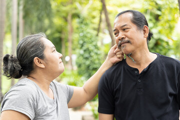 Angry old wife twisting the ear of senior husband, concept of senior couple with regular fight and...