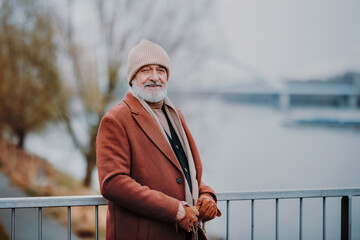 Elegant senior standing near the river, during cold winter day.