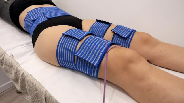 Girl lying on bed receiving electrostimulation therapy at beauty salon.