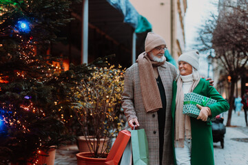 Happy senior couple enjoying christmas market, buying gifts.