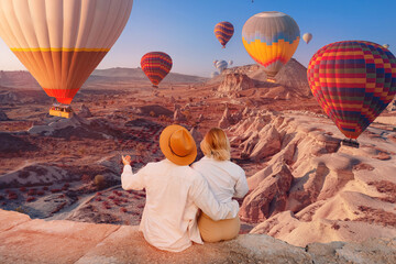 Romantic vacation Happy traveler couple watching sunrise with hot air balloons in Cappadocia Turkey...