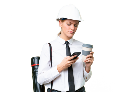 Young architect caucasian woman with helmet and holding blueprints over isolated background holding coffee to take away and a mobile