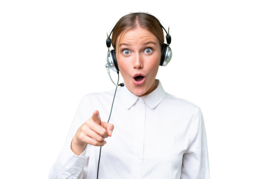 Telemarketer caucasian woman working with a headset over isolated background surprised and pointing front