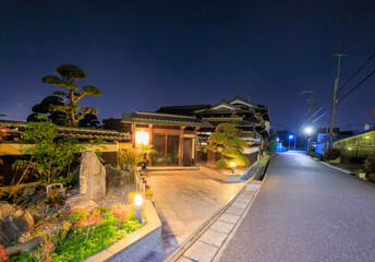 Traditional Japanese house and garden on quiet street at night