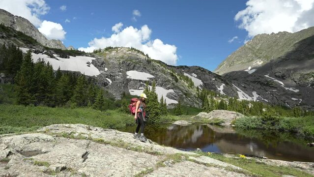 Young Female Hiker With Backpack Walking by Scenic Glacial Lake on Sunny Summer Day