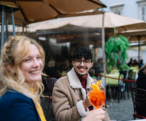 Selective focus on a smiling young Arab boy sitting with his girlfriend while they're having drinks