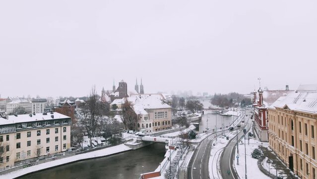 Winter aerial view with snowfall on Tamka island and Roman Catholic parish church NMP on the Sand in Wroclaw 4k
