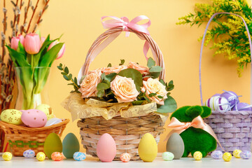 Easter composition. Basket with flowers and eggs toy rabbit on the table.
