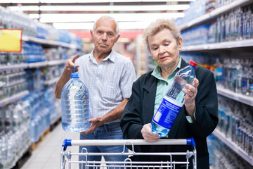 mature european spouses selects bottled water in the department of supermarket