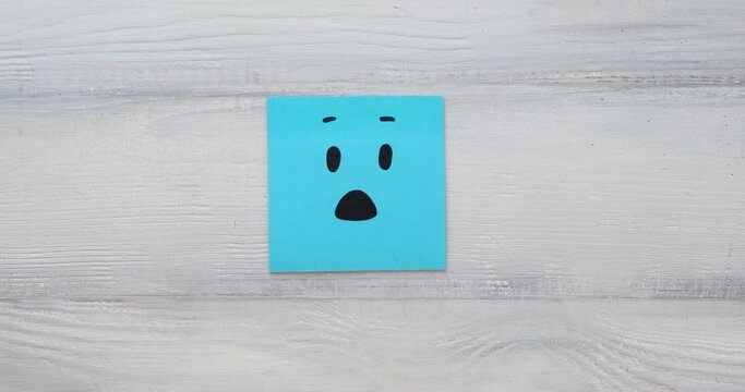 Basic emotions are joy, sadness, anger, fear or surprise. Four colorful squares with emotions on a wooden background. 4K looped stop motion animation
