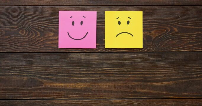Basic emotions are joy, sadness, anger, fear or surprise. Four colorful squares with emotions on a brown wooden background. 4K looped stop motion animation