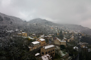 Aerial winter landscape of dense historic center of Thiers town in Puy-de-Dome department, Auvergne-Rhone-Alpes region in France. Rooftops of old buildings and narrow streets at snowfall