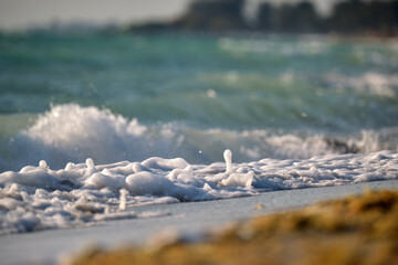 Seaside sand beach with foamy waves crushing on shore