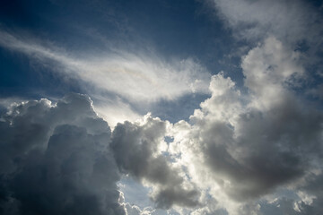 White fluffy cumulonimbus clouds forming before thunderstorm on summer blue sky. Changing stormy cloudscape weather