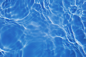 Defocus blurred transparent blue colored clear calm water surface texture with splashes and bubbles. Trendy abstract nature background. Water waves in sunlight with caustics. Blue water shinning 