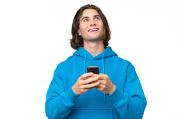 Young handsome man isolated on green chroma background using mobile phone and looking up