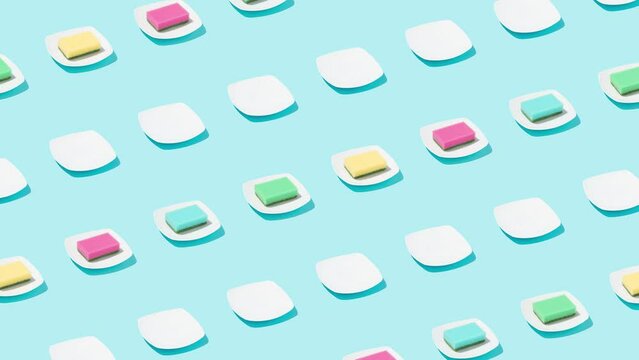 Colorful kitchen sponges and white plates on bright blue background. Minimal cleaning concept. Creative 4k loop video. 