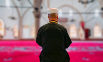 Muslim cleric imam reading quran in mosque at sunset
