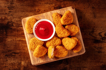 Chicken nuggets on a rustic wooden table, overhead flat lay shot. A crispy appetizer at a...