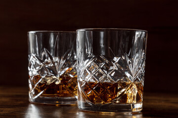 Whiskey in glasses with ice. Bourbon whisky on rocks on a dark background, elegant drinks