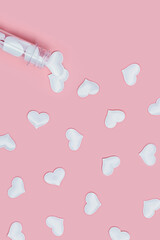 Test tube with white hearts around on pink background. Love concept.
