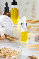 Oils, bath brush, towel and wheat sprouts on the cosmetic table in the bathroom. A set of organic cosmetics in glass vials with dropper for skin and hair care. The concept of self care and spa