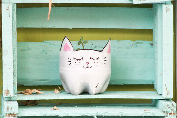 Macetero en forma de gatito en fondo verde turquesa