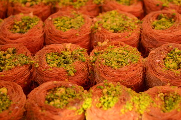 Fototapeta premium Baklava with pistachios. Traditional oriental sweets made from syrup and honey. Close-up, oriental market stall
