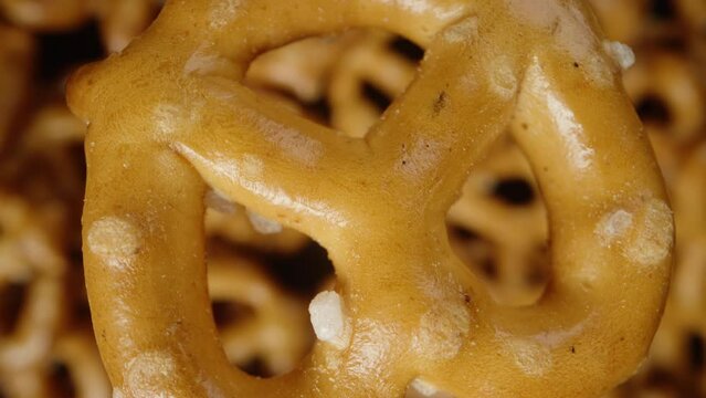 a mini pretzel spinning slowly and falling on a bunch of other pretzels. Close-up from above
