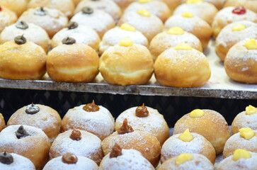 Fresh donuts with chocolate, jam at the bakery display for celebration. Sufganiyot - Israeli Donuts. Selective focus. Symbol of sweet Hanukkah donut - Sufganiyah. 