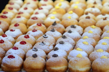 Fresh donuts with chocolate, jam at the bakery display for celebration. Sufganiyot - Israeli Donuts. Selective focus. Symbol of sweet Hanukkah donut - Sufganiyah. 