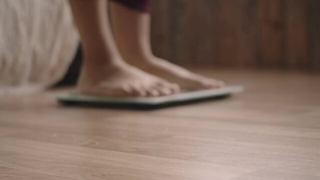 Blurry bottom view, the person foot stands on the scales, the measuring tape falls in the foreground. Concept of excess weight, weight loss