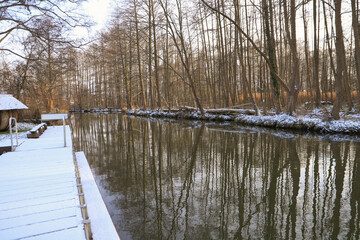 A frozen flow, a snow covered bench and a wooden bridge in winter in Spree forest, Germany