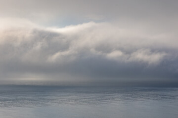 Fototapeta na wymiar Fog clouds low above the calm water of the Irish Sea. 