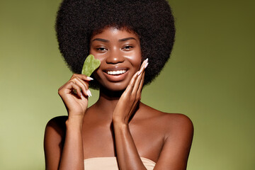 Face building. Facial contour. Gua Sha jade skin treatment. African American model making face...