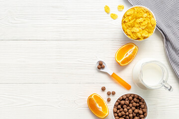 Kids breakfast with corn flakes, milk and orange, top view