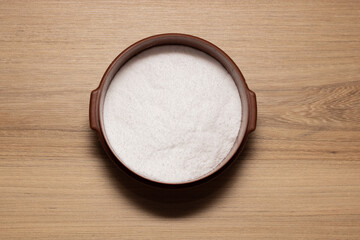 Brown container with white salt for seasoning. Salty concept on wooden table