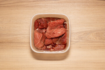 Raw meat in transparent container. High quality photo with beef meat on wooden table