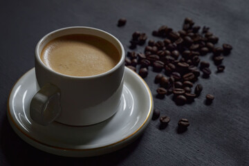 Hot cappuccino and coffee beans on a dark background