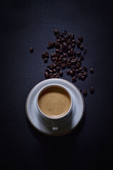 Hot cappuccino and coffee beans on a dark background