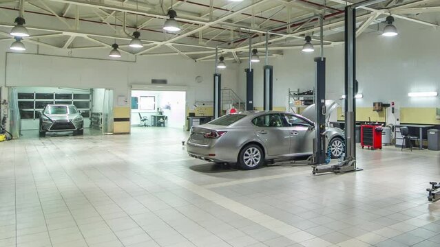 Cars moves on lifts in modern service station and men repair cars timelapse hyperlapse. Car wash boxes on background