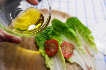 Olivenöl mit Tomaten und Salat auf einer Holzplatte