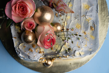  cake on a golden tray on a blue table, decorated with roses and flowers, 