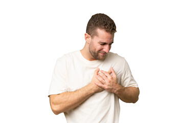 Young handsome caucasian man isolated on green chroma background having a pain in the heart