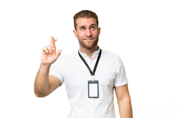 Young caucasian man with ID card isolated on green chroma background with fingers crossing and wishing the best