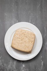 raw tofu block on white small dish on ceramic